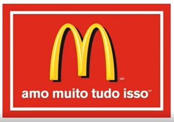 logomarca do McDonald's. sobre um fundo vermelho, a letra "M" amarela em traços arredondados, com uma sombra preta, e os dizeres "amo muito tudo isso" em letras brancas logo abaixo.