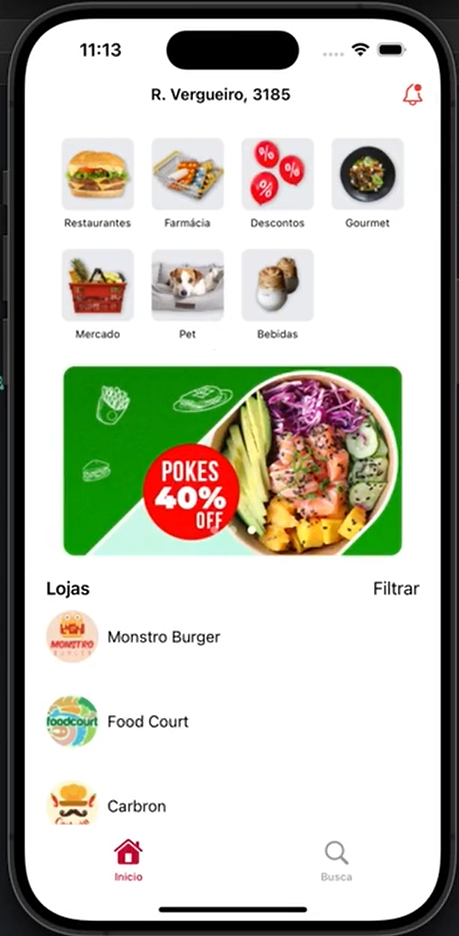 Mockup da página inicial do aplicativo Chef Delivery. Na parte superior da tela, barra de navegação com endereço 'R. Vergueiro, 3185' e ícone de sino de notificações. Abaixo, uma grade com ícones de categorias de produtos e seus nomes: Restaurantes, Farmácia, Descontos, Gourmet, Mercado, Pet, Bebidas. Abaixo, um banner de propaganda de Pokes com 40% de desconto. Depois, uma lista de título 'Lojas' contendo os restaurantes 'Monstro burger', 'Food court' e 'Carbron', nessa ordem. Por fim, uma barra inferior com um ícone de casa rotulado 'Início' e um ícone de lupa rotulado 'Busca'.