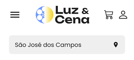 Contêiner com o cabeçalho de navegação do site Luz & Cena na versão responsiva. A partir da esquerda, um ícone de menu hambúrguer, o logo 'Luz & Cena', os ícones de carrinho de compras e conta de usuário. Abaixo desses itens, um campo de localização com o local 'São José dos Campos' selecionado, junto a um ícone de marcador de localização à direita.